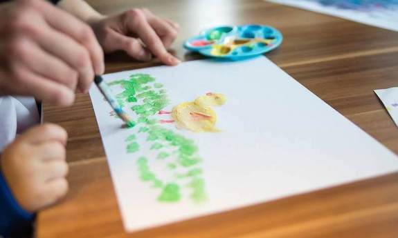 Kind und erwachsene Person malen auf weissem Papier