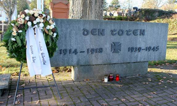 Blumenkränze an einem Denkmal auf dem Friedhof in Quierschied