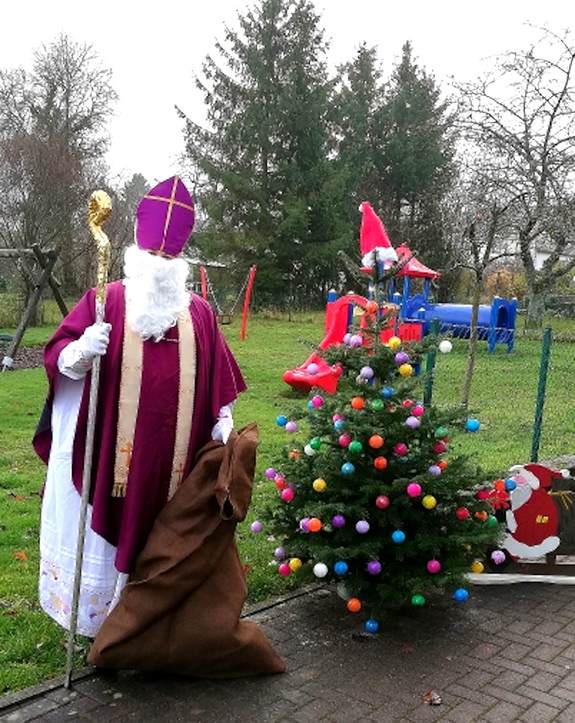 Nikolaus steht neben Weihnachtsbaum