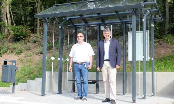 In der neuen Haltestelle, Glashäuschen "Auf der Brach" stehen Dipl.-Ing. Wolfgang Kallenbach mit Bürgermeister Lutz Maurer